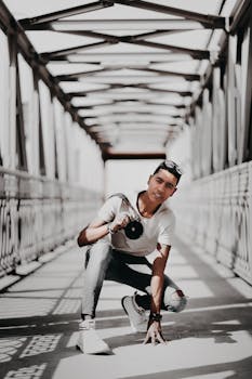 一位时尚的成年男性在现代风格的桥上手持相机摆姿势，展现都市时尚