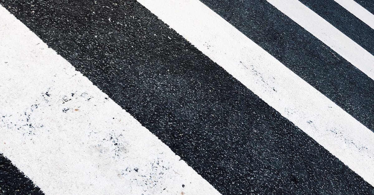 Photo by Teddy Yang Close-up of black and white pedestrian crossing stripes on asphalt, creating a pattern.