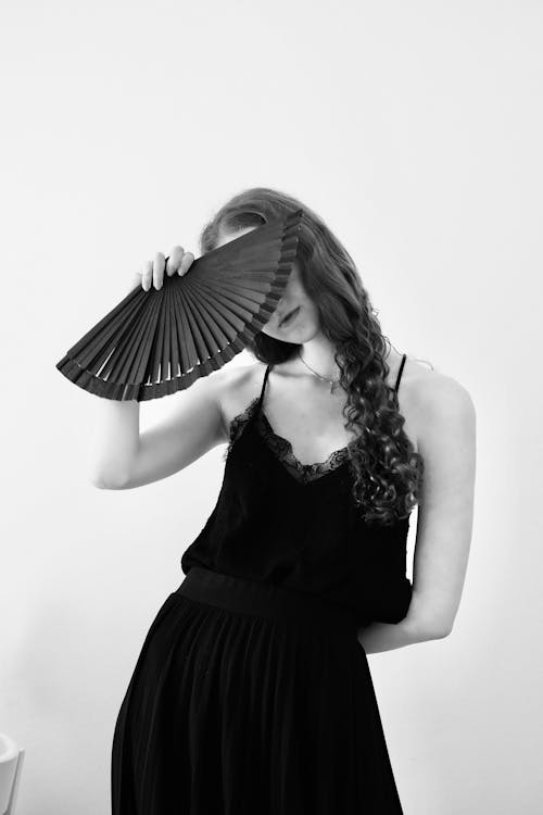 A woman in a black dress holding a fan