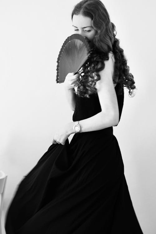 Free A woman in a black dress holding a fan Stock Photo