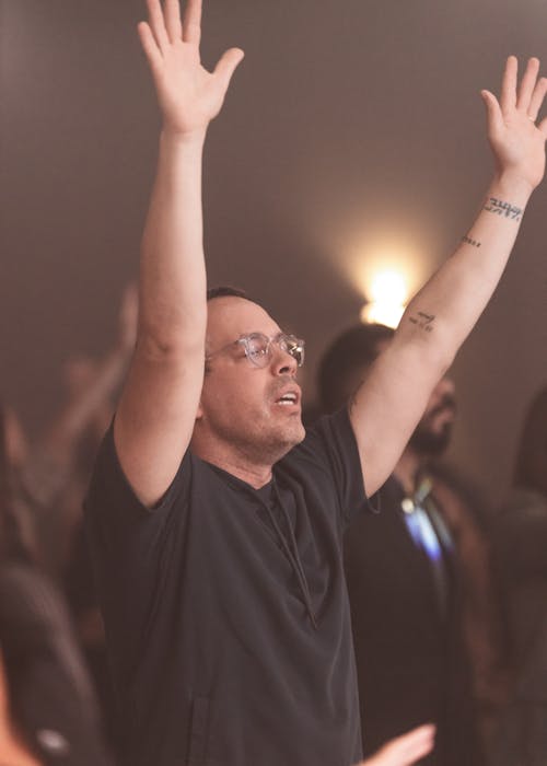 Free A man raising his hands in the air at a church Stock Photo