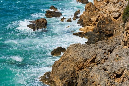 Free Explore a stunning rocky coastline with crashing ocean waves under the sun. Stock Photo