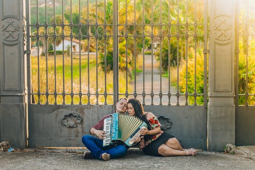 Woman And Man Playing Musical Instrument Near Gate