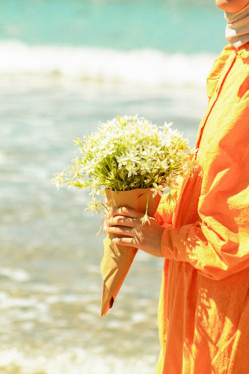 A woman in an orange dress holding a bouquet of flowers