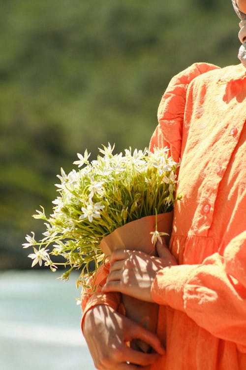 A woman in an orange shirt holding flowers
