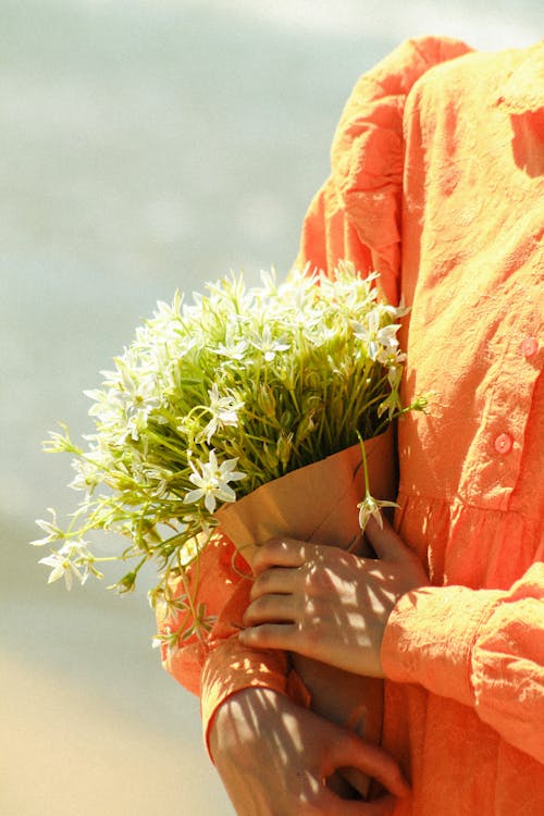 A woman in an orange dress holding flowers