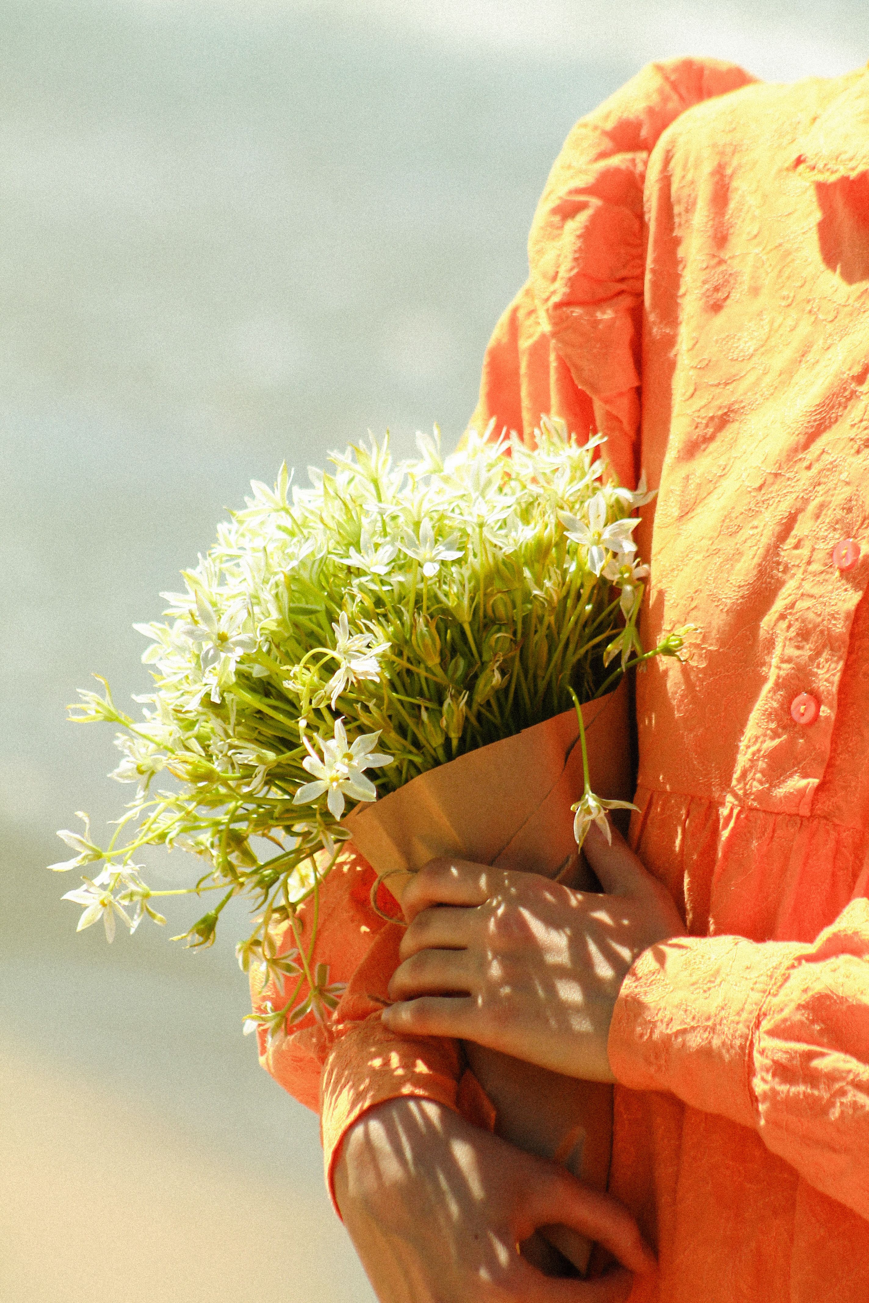 Woman Holding a Bouquet of Flowers on a Beach · Free Stock Photo