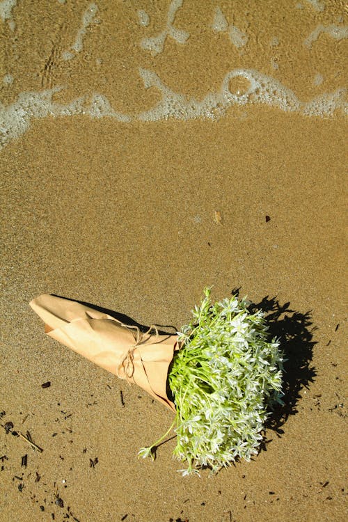 A bouquet of flowers on the beach with sand