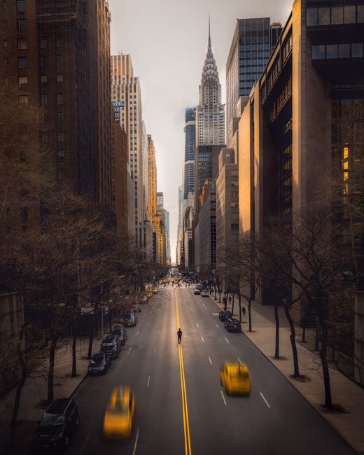 A bustling New York City street featuring yellow taxis, modern skyscrapers, and iconic architecture.