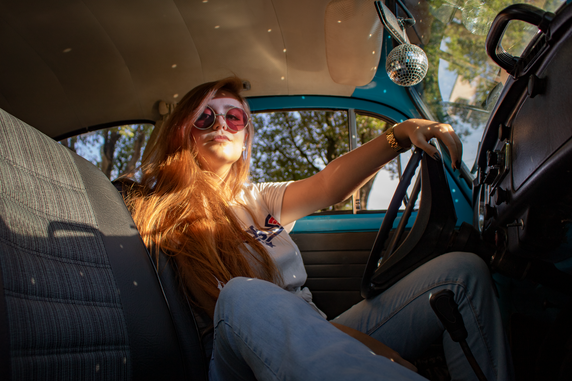 Young woman with sunglasses enjoying a sunny drive in a vintage Volkswagen Beetle.