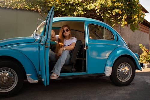 Woman Wearing White Shirt Sitting Inside Blue Volkswagen Beetle