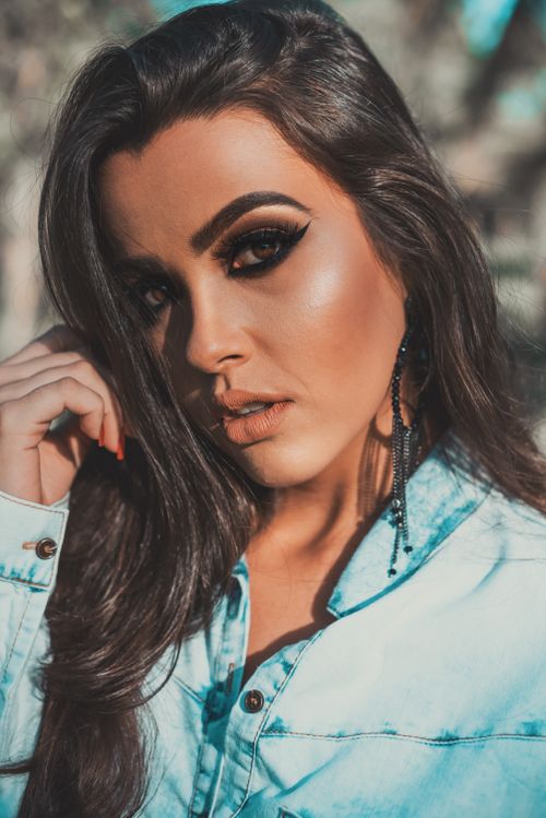 Free Close-up portrait of a beautiful woman with striking makeup and denim shirt outdoors. Stock Photo