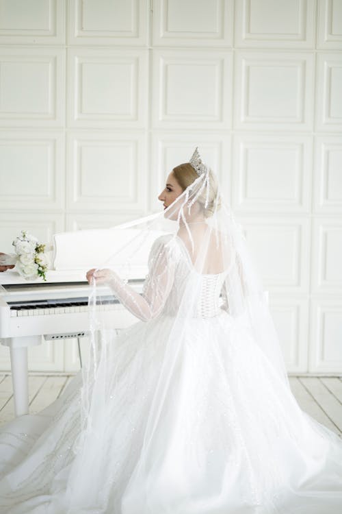 Free A bride in a wedding dress is sitting at a piano Stock Photo