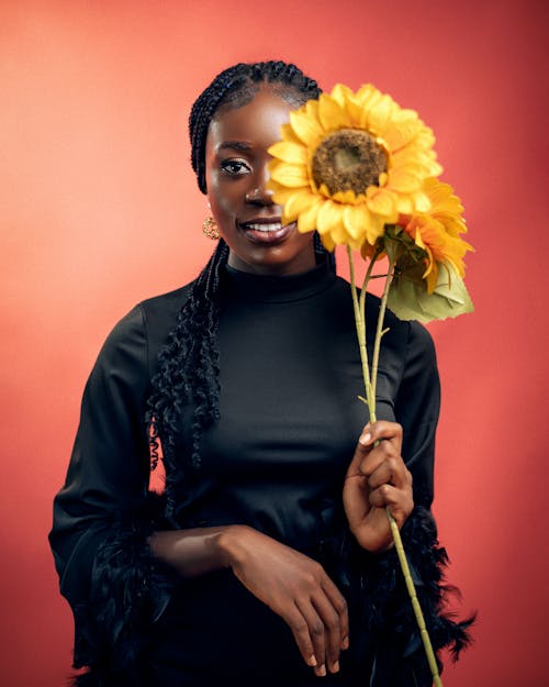 Free A woman holding a sunflower in front of her face Stock Photo