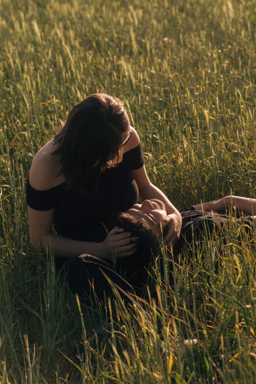 Free A couple enjoying peaceful moments lying together in a grassy field during the day. Stock Photo