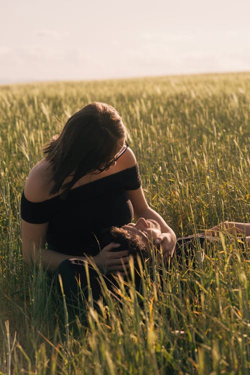 Free A woman sitting in a field with her baby Stock Photo