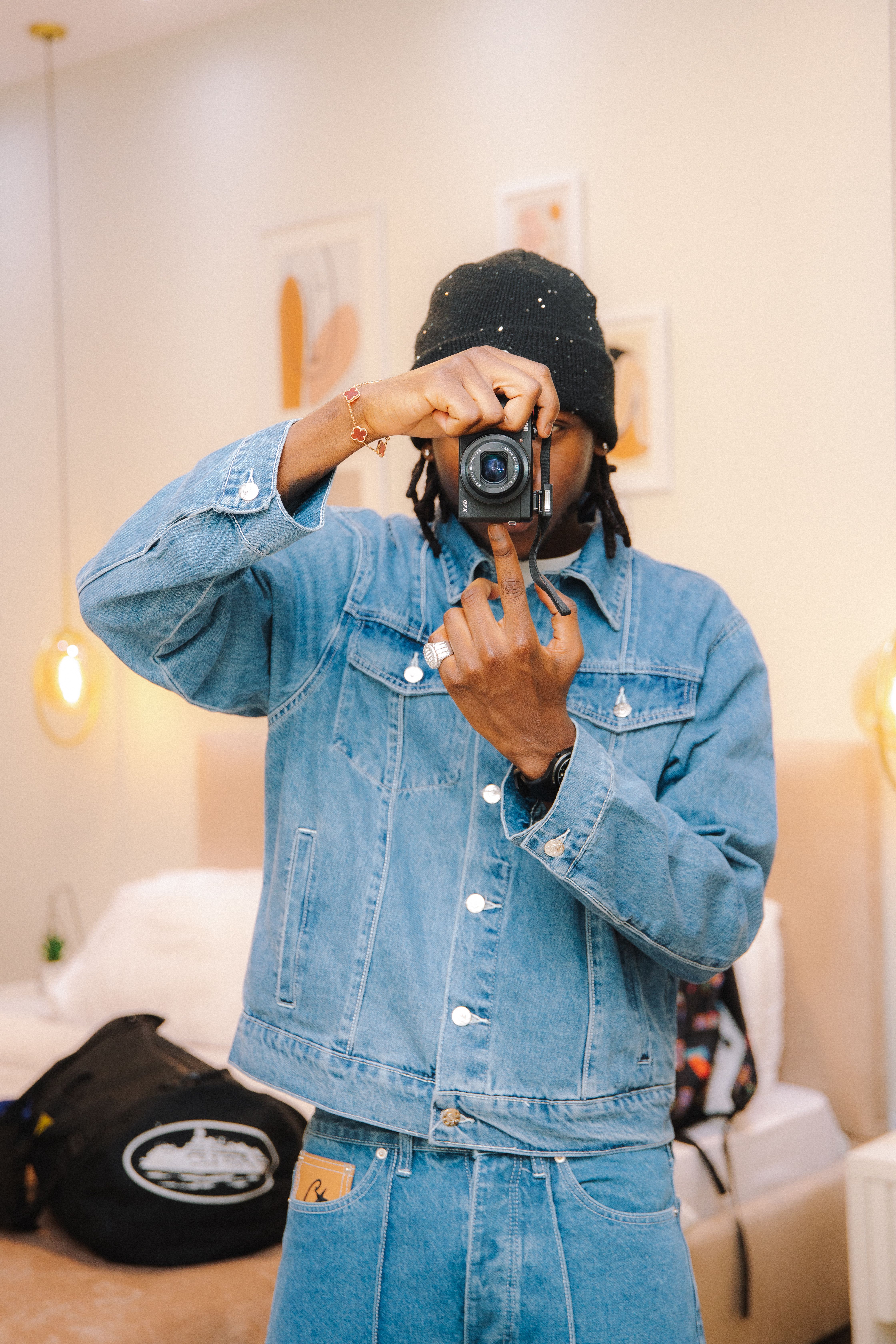 A person in a denim jacket taking a picture indoors with a camera, a scene capturing a casual photography moment.