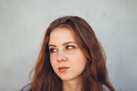 特写肖像中，一位年轻女子扭头看去，带着内省的表情