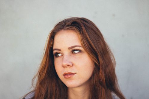 Free Close-up portrait of a young woman looking away with an introspective expression. Stock Photo