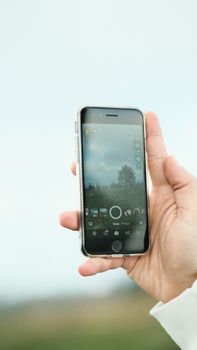 Hand holding a smartphone showing a scenic view, ideal for technology or travel concepts.