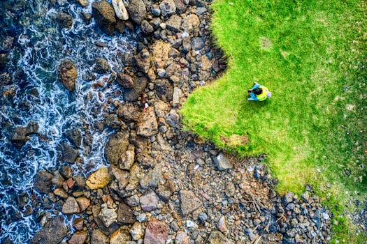 A stunning aerial shot of a rocky shoreline meeting green grass in Banten, Indonesia.