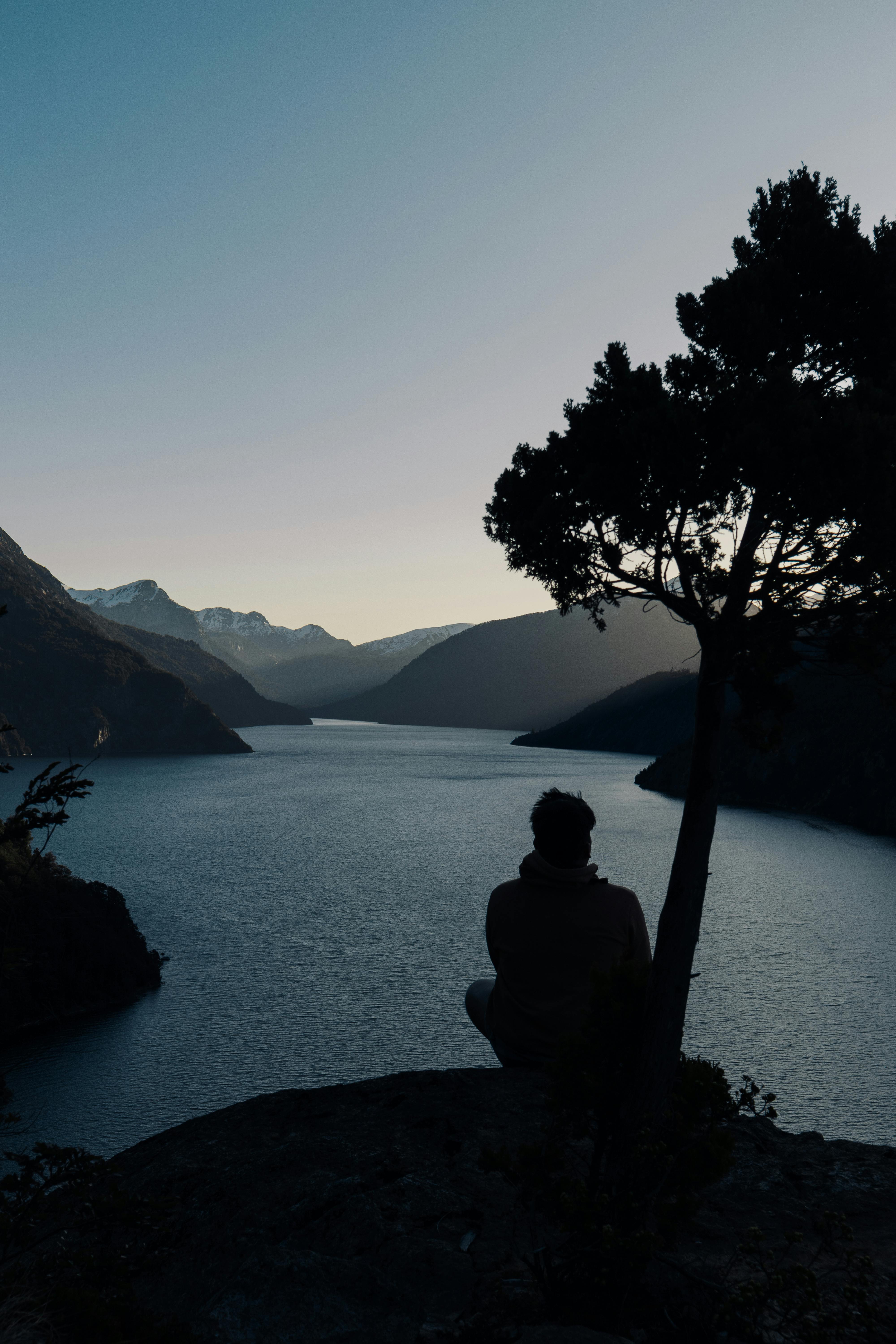 A serene silhouette overlooks a lake and mountains at sunset in Bariloche, Argentina.