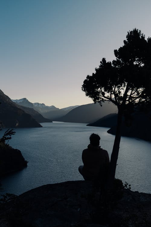A person sitting on a rock overlooking a lake