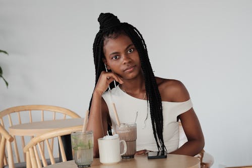 Free A woman with dreadlocks sitting at a table with a drink Stock Photo