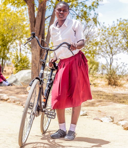 Mujer Sosteniendo Bicicleta Negra Cerca De árboles De Hojas Verdes