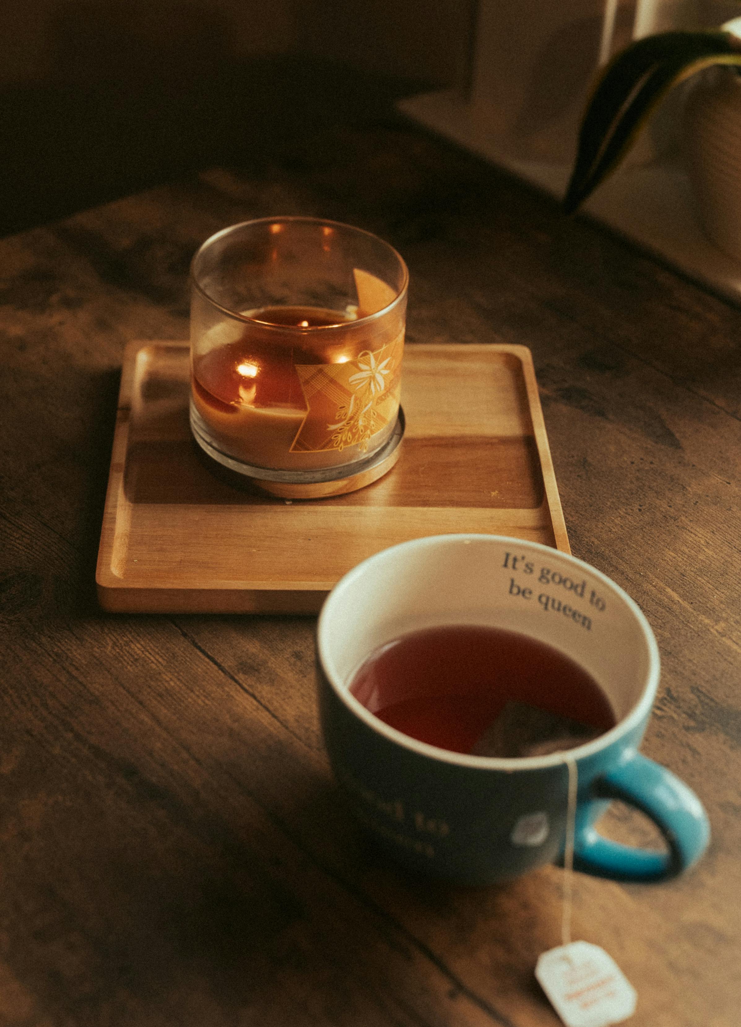 A warm, intimate scene featuring a candle and a cup of tea on a wooden table.