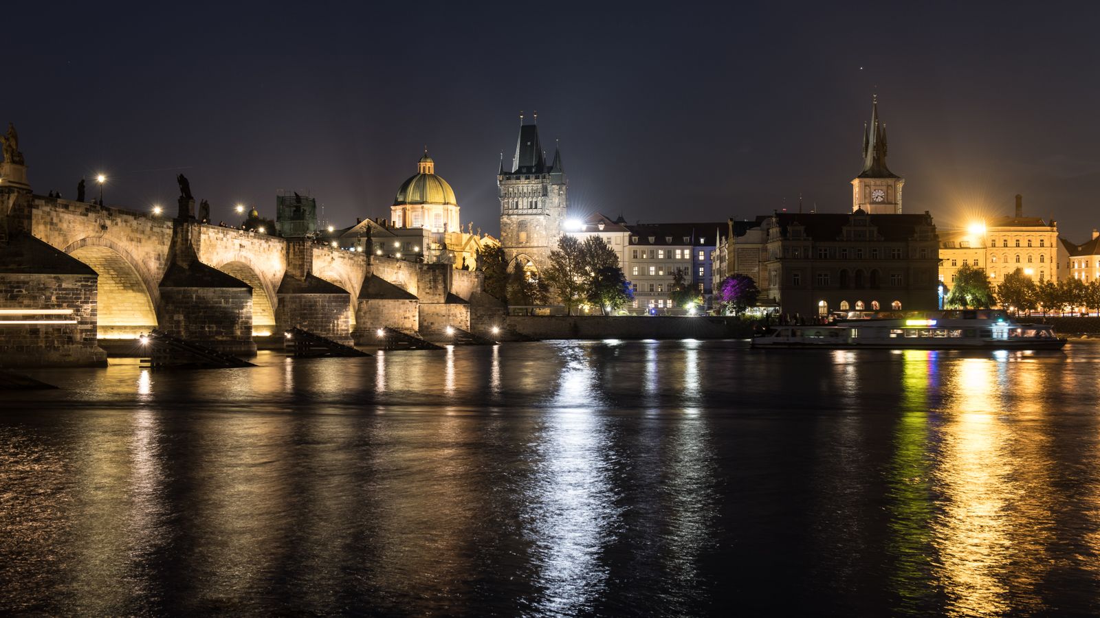 Stunning night view of Charles Bridge and Prague skyline with reflections on the Vltava River