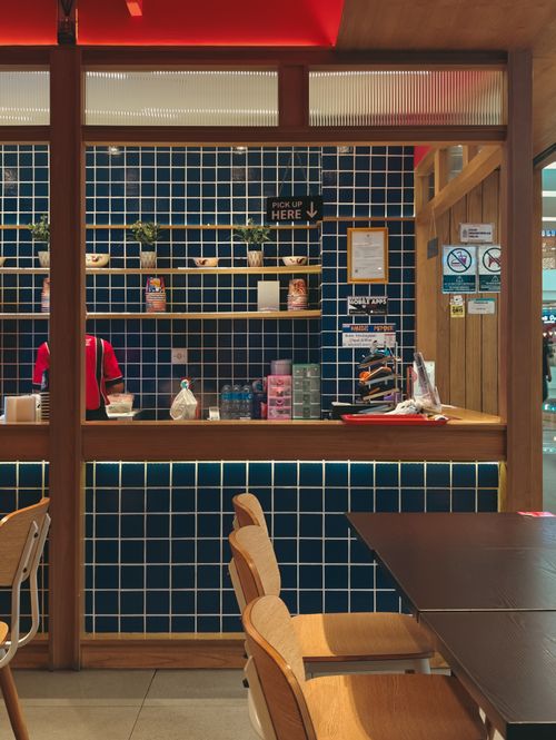 Free Warm and inviting Indonesian café interior featuring a blue tiled counter and wooden furniture. Stock Photo