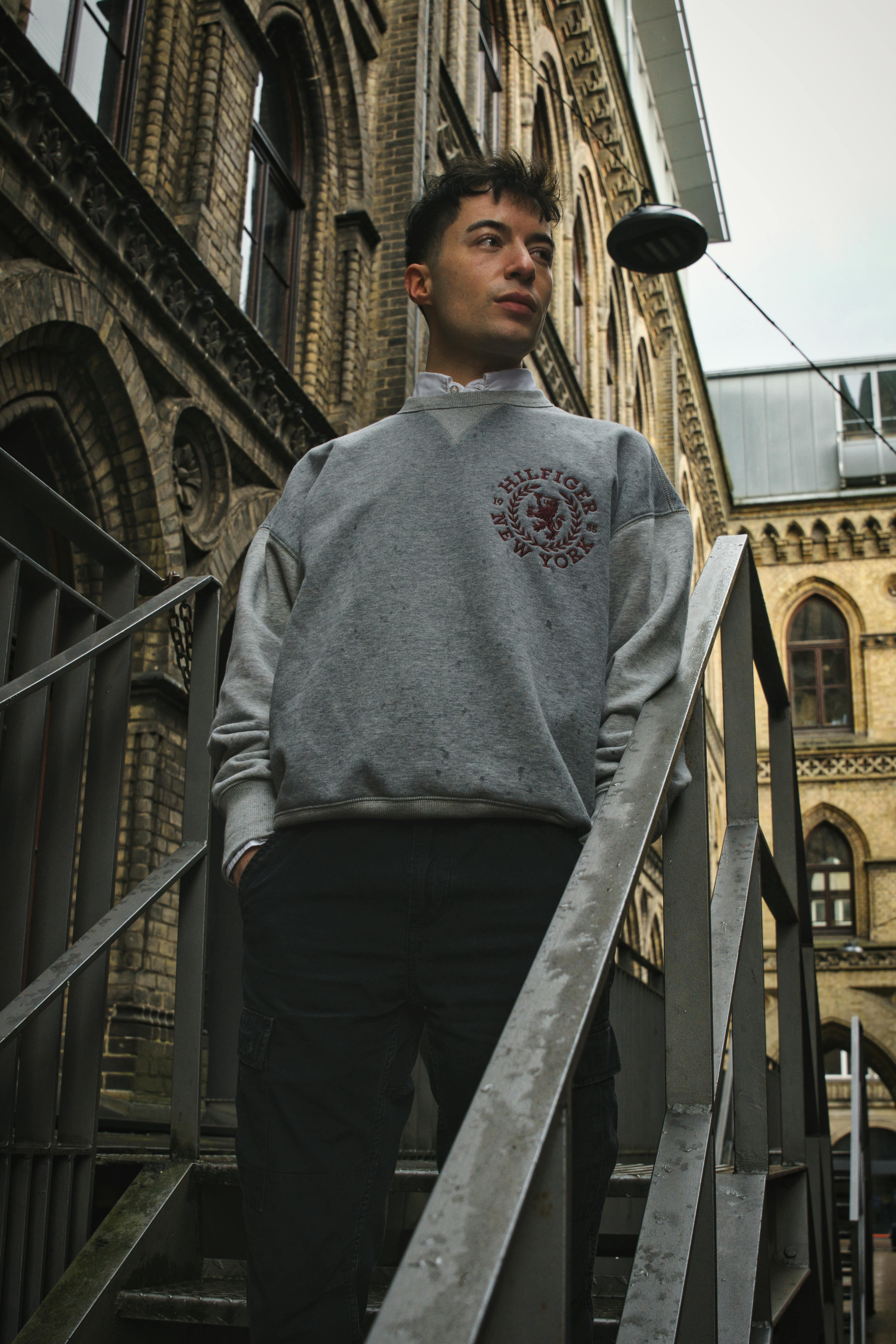 Stylish male model posing in a pullover against Bremen's architectural backdrop. Perfect for urban fashion themes.