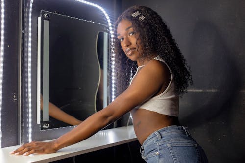 Free A woman in jeans and a white shirt is standing in front of a mirror Stock Photo