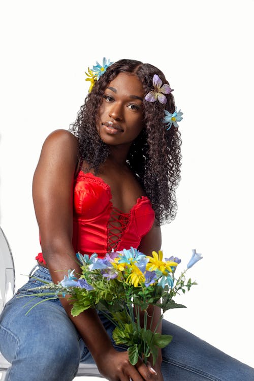 Free A woman in a red top and jeans holding flowers Stock Photo