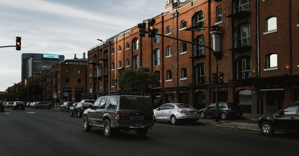 Street view of busy traffic in Buenos Aires with historic brick buildings and stoplights.
