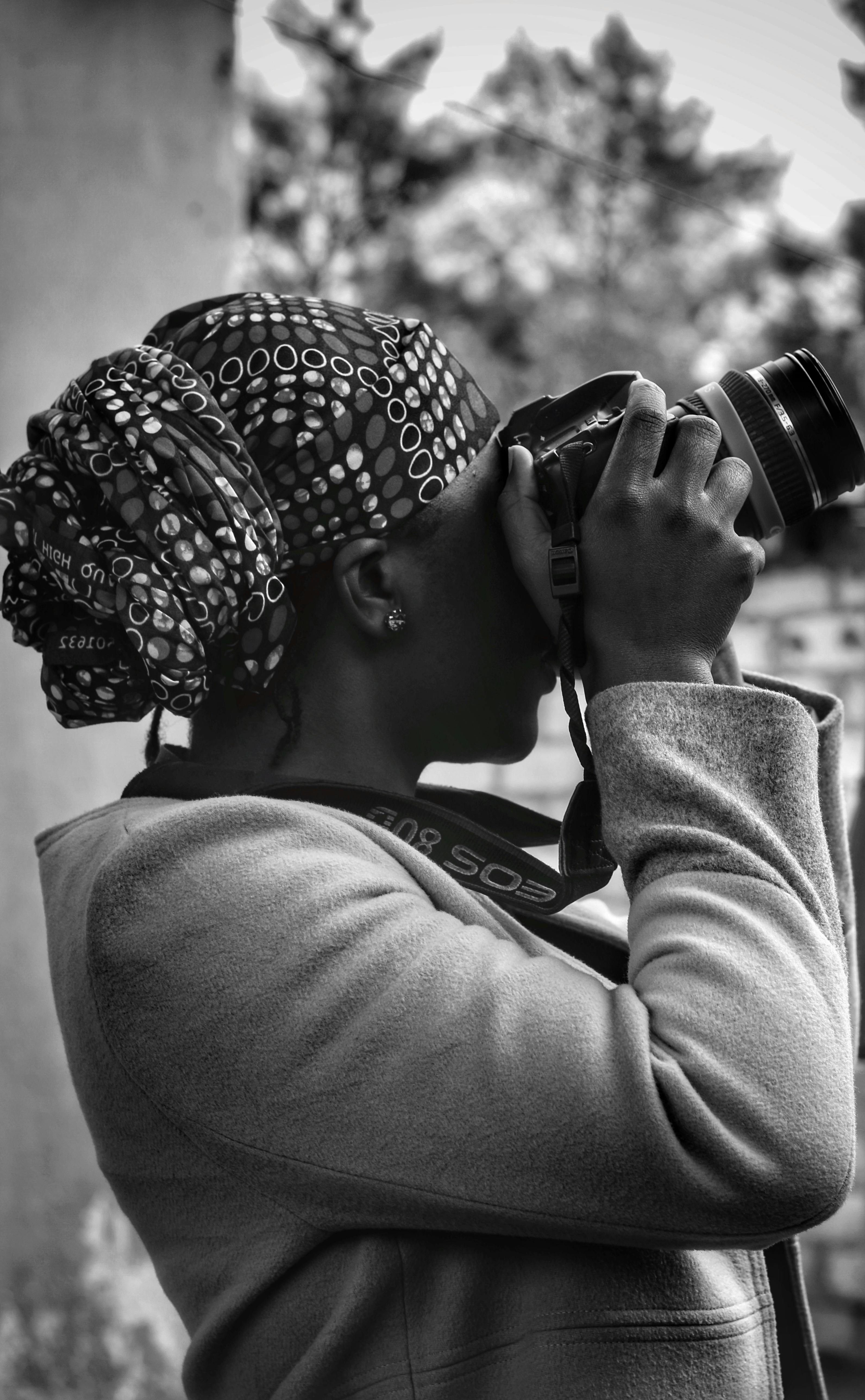 A black woman in Zambia taking photos with a camera, wearing a headscarf.