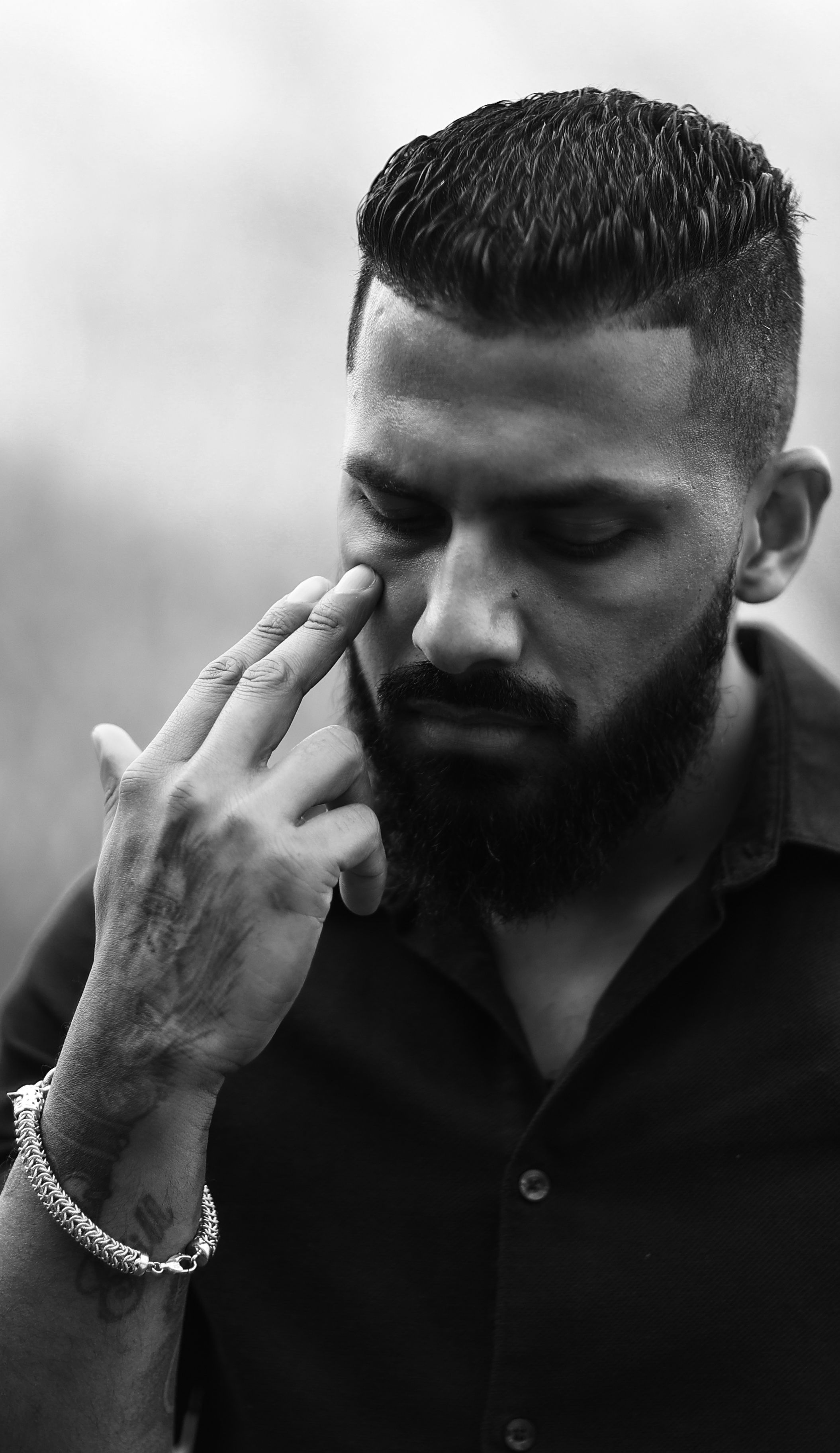 Black and white portrait of a thoughtful man touching his face, exuding a serious demeanor.