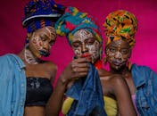 三位女性的肖像引人注目，她们戴着色彩缤纷的头巾和复杂的面部彩绘，展现了非洲时尚