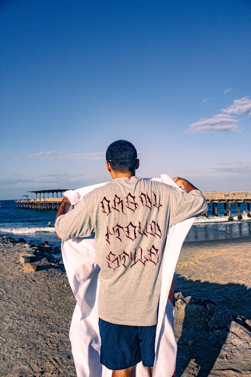 Free Back View of Man Standing with Blanket on Beach Stock Photo