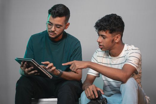Two men in a studio discussing work using a tablet, highlighting collaboration and teamwork.
