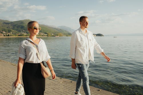 A man and woman walking along the water