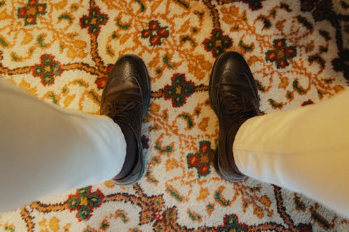 A person's legs are on a rug with a pattern