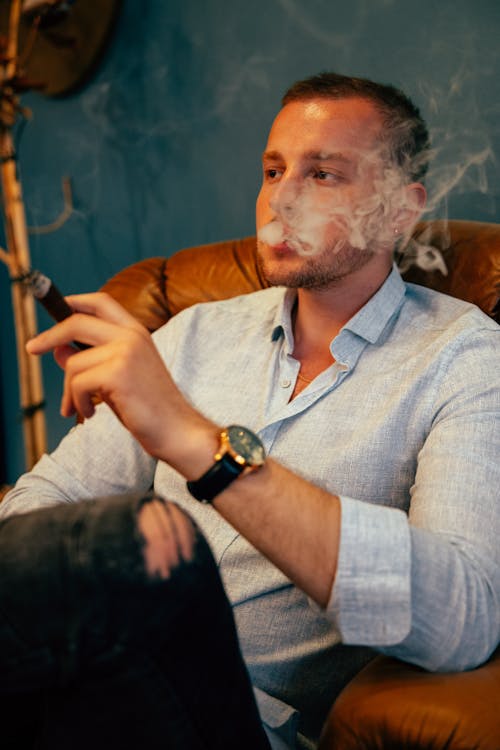 A man sitting in a chair smoking a cigarette