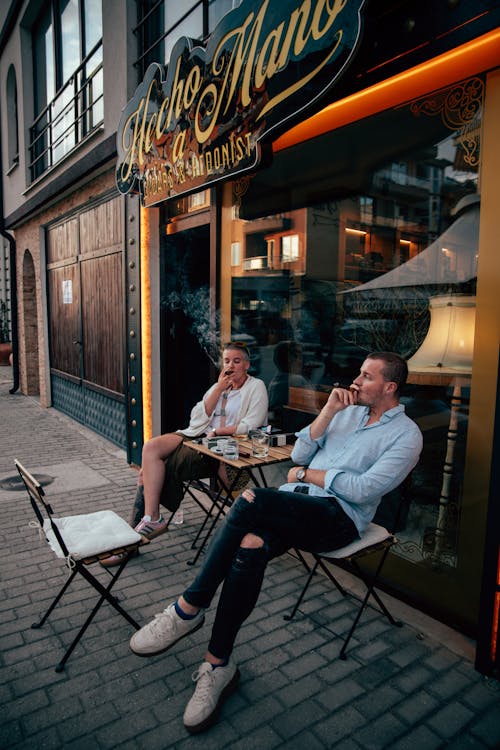 Two men sitting outside a restaurant smoking