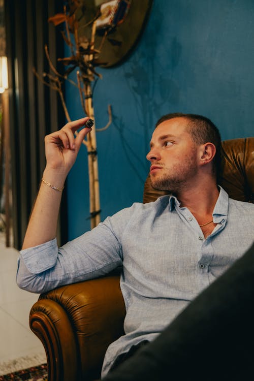 Free A man sitting in a chair smoking a cigarette Stock Photo