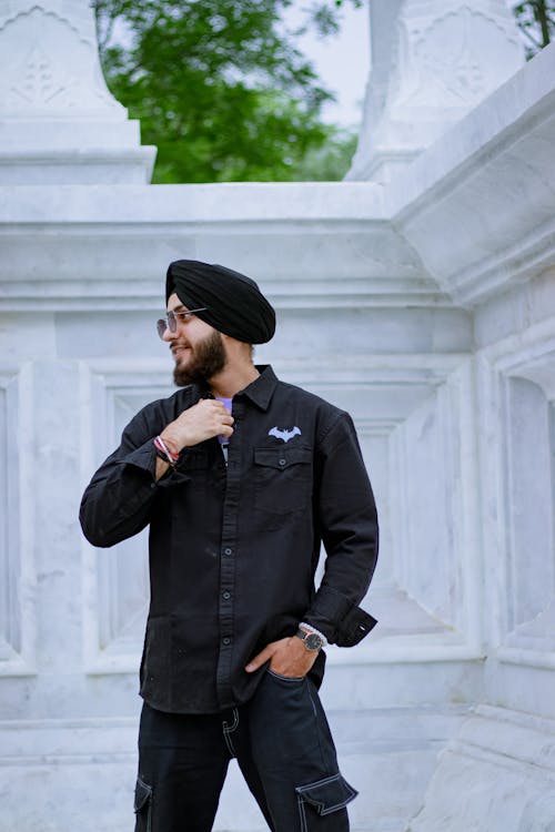 A man in black shirt and black pants standing in front of a white pillar