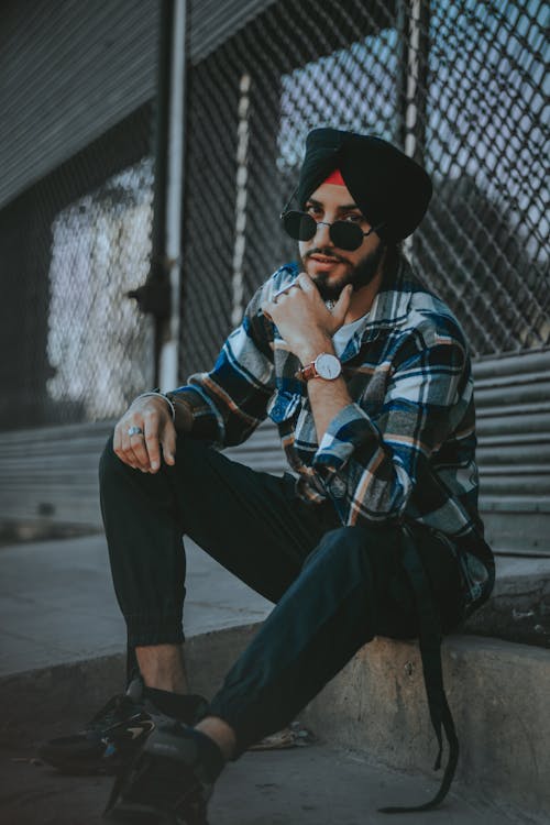 A man in a plaid shirt and sunglasses sitting on a bench