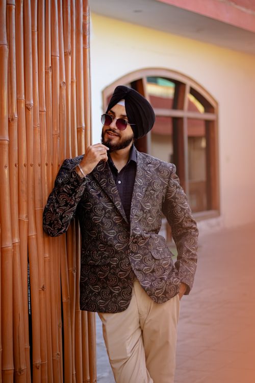 Free Stylish man with a turban and sunglasses posing against a wall, showcasing traditional elegance. Stock Photo
