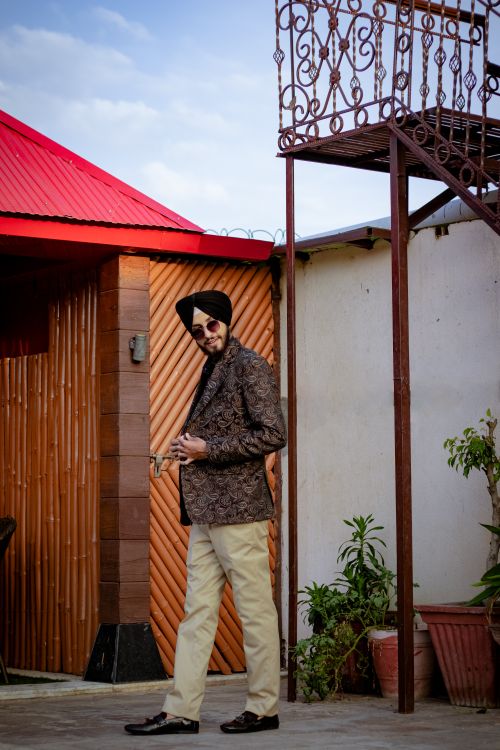 Free Fashionable man in jacket and turban poses outdoors by a textured wall, exuding elegance. Stock Photo